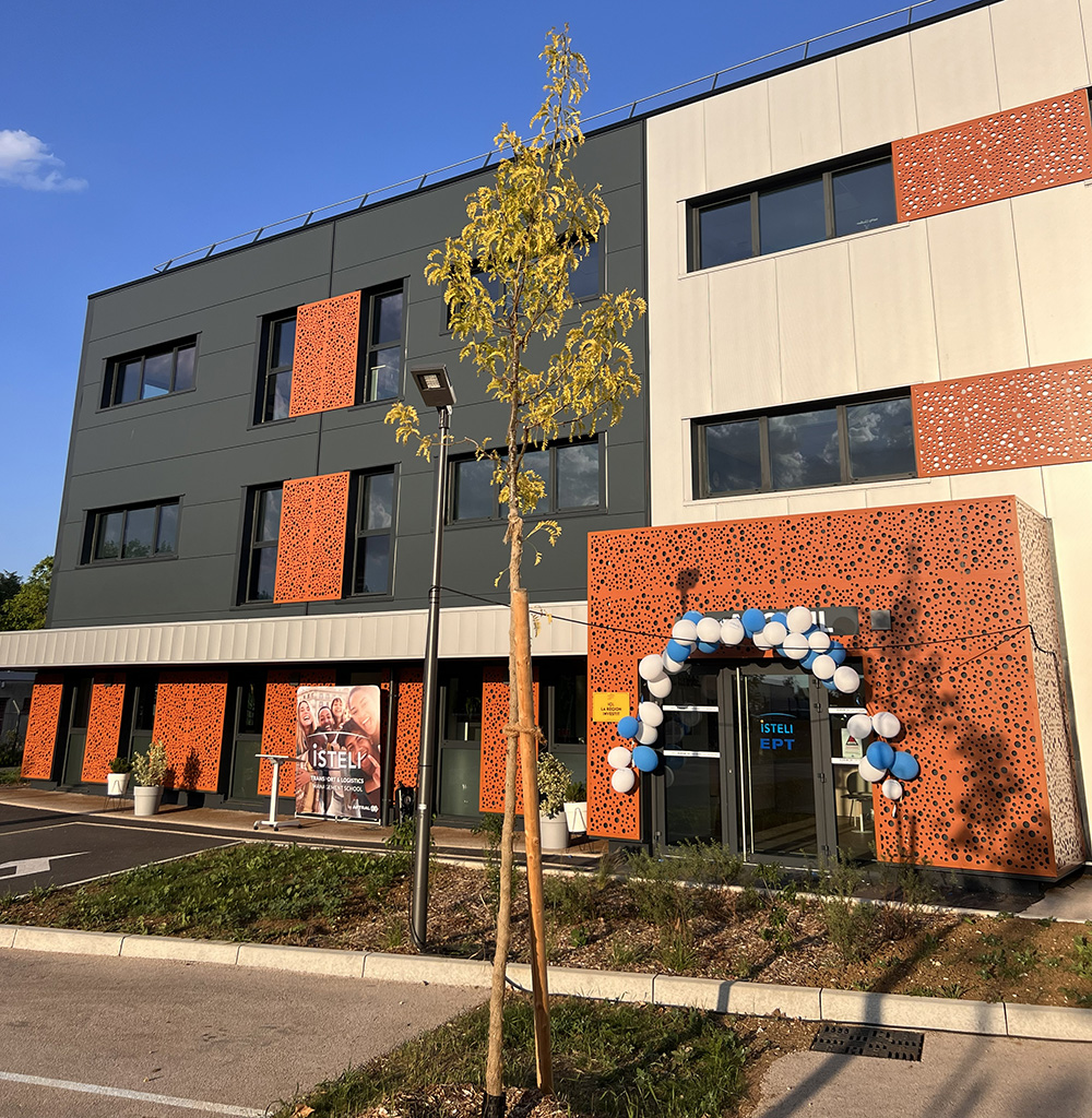 Un bâtiment moderne avec des façades colorées, un arbre nouvellement planté et une entrée décorée de ballons.