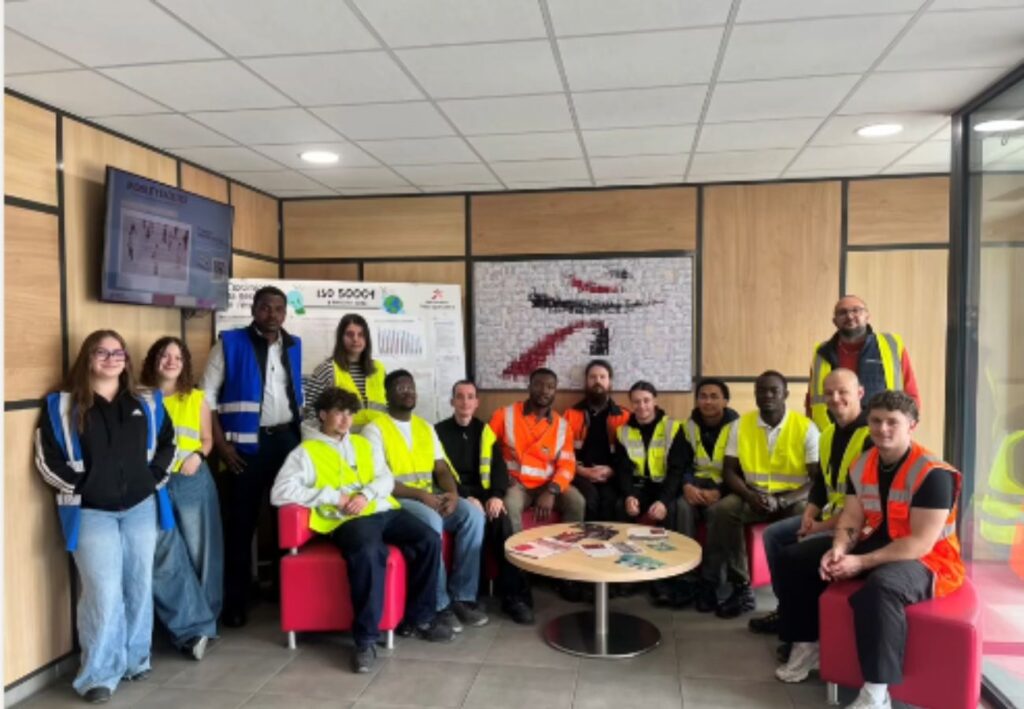 Un groupe de personnes portant des gilets de sécurité se tient dans un espace intérieur autour d'une table basse.