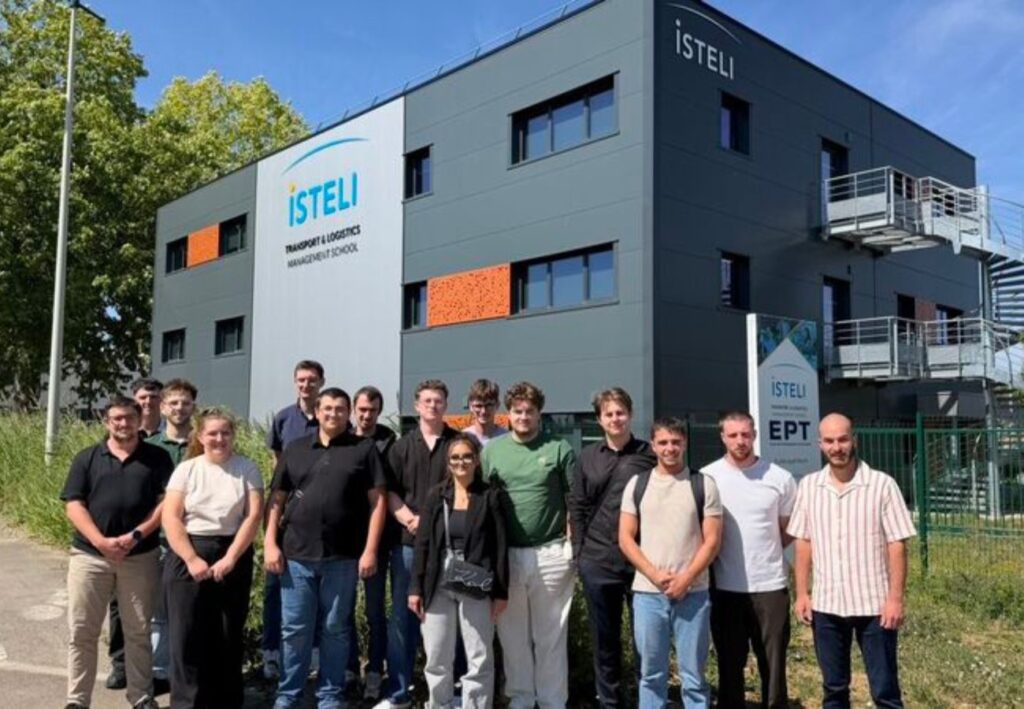 Un groupe d'étudiants pose devant le bâtiment de l'école ISTELI dédié à la gestion du transport et de la logistique.