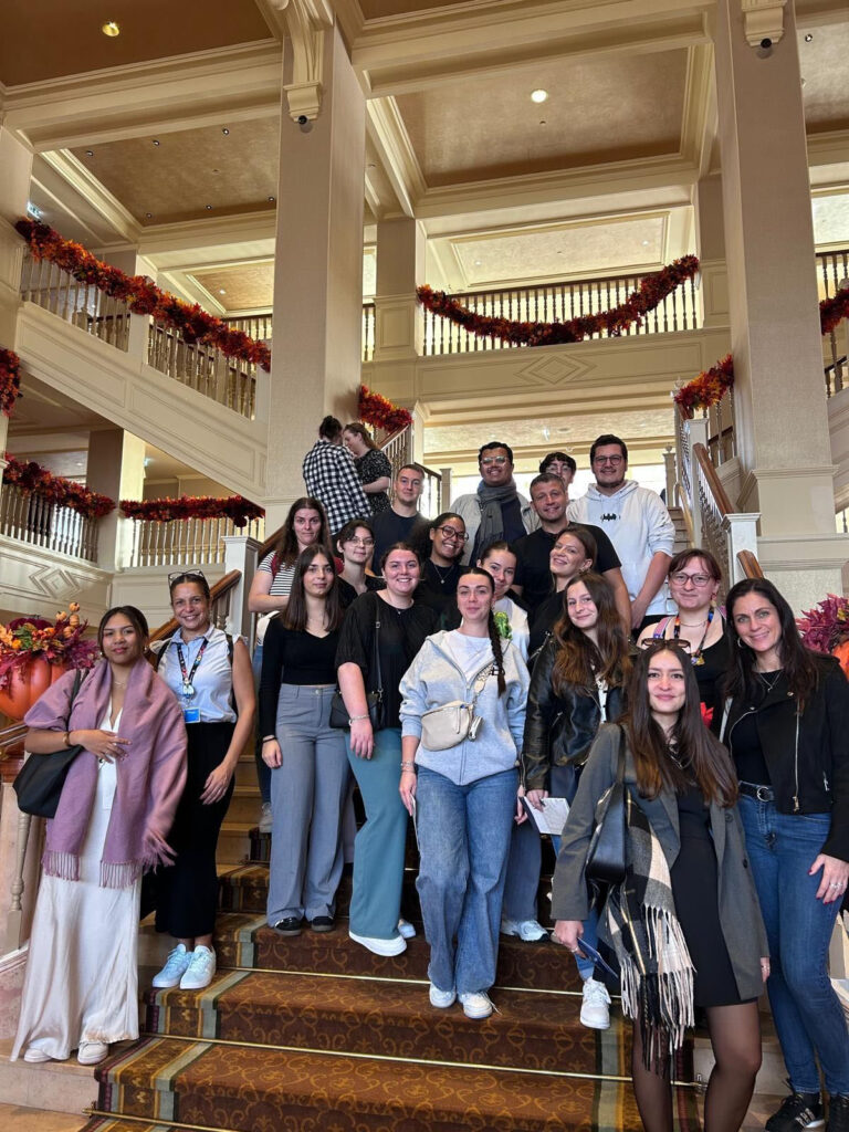 Un groupe de personnes se tient sur un escalier dans un hall décoré avec des ornements d'automne.