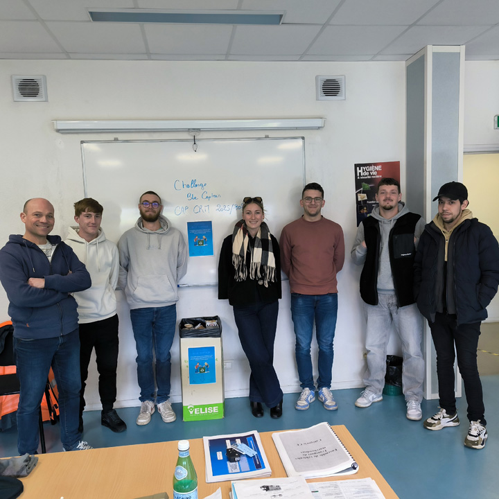 Un groupe de personnes se tient debout devant un tableau blanc dans une salle de classe.
