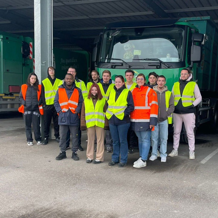 Un groupe de personnes portant des gilets de sécurité réfléchissants pose devant un camion dans un garage.
