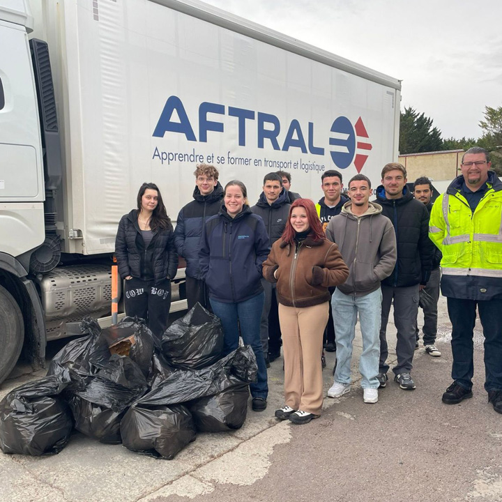 Un groupe de jeunes adultes pose devant un camion de transport avec plusieurs sacs poubelles noirs à leurs pieds.