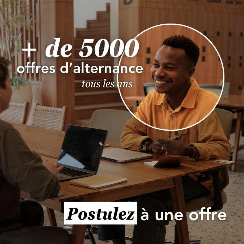 Une personne souriante participe à une discussion autour d'une table, avec des ordinateurs portables et des offres d'alternance affichées à l'écran.